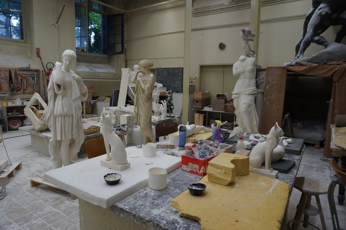 Atelier de moulage : plâtres en cours, moules et outils sur les établis, sans personnage