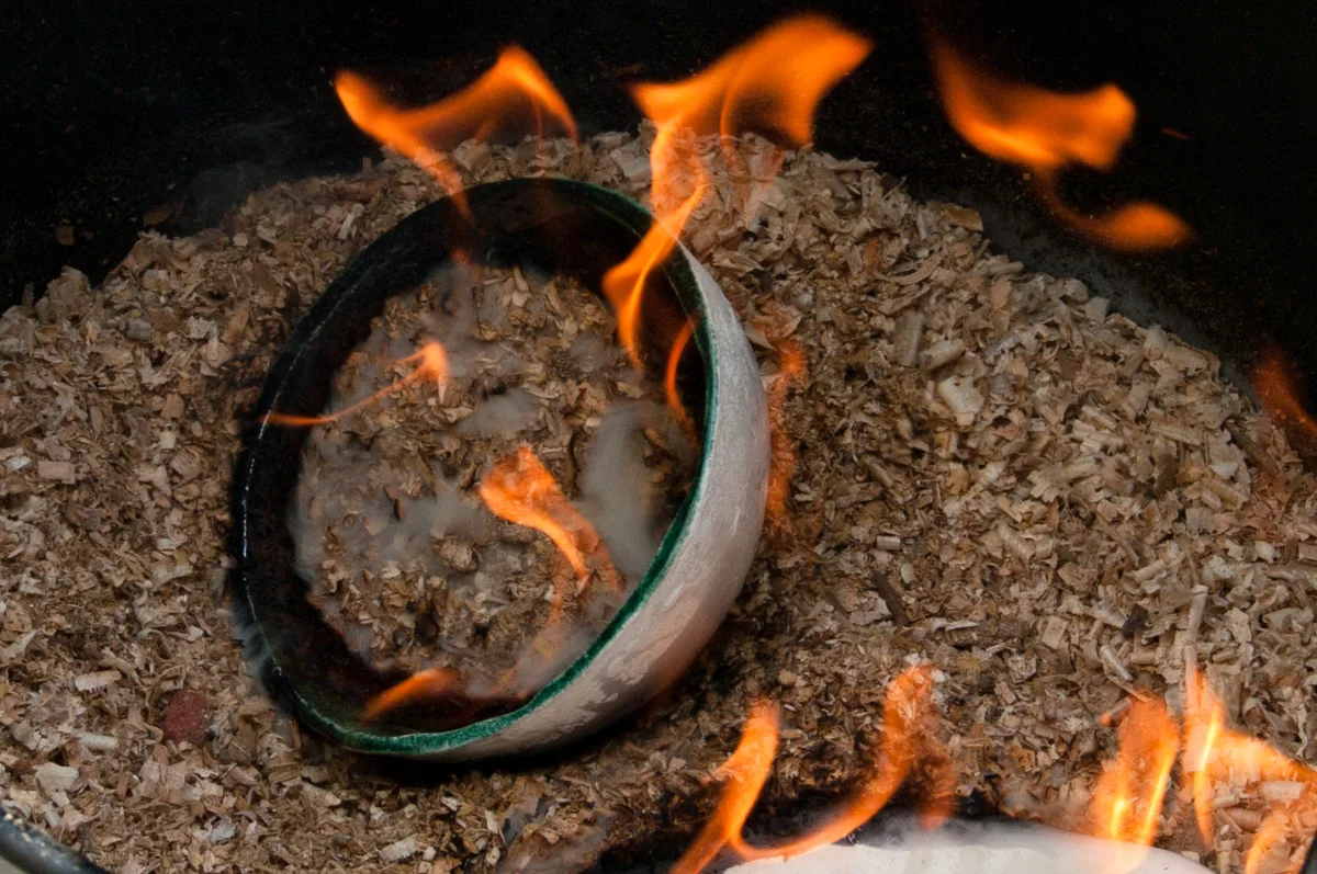 Raku : pièce de céramique incandescente enfumée dans la sciure enflammée
